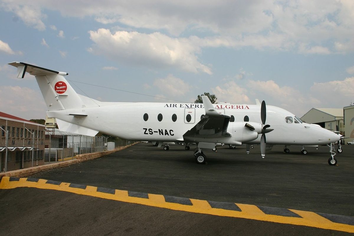 White turboprop aircraft with registration ZS-NAC parked at airport terminal