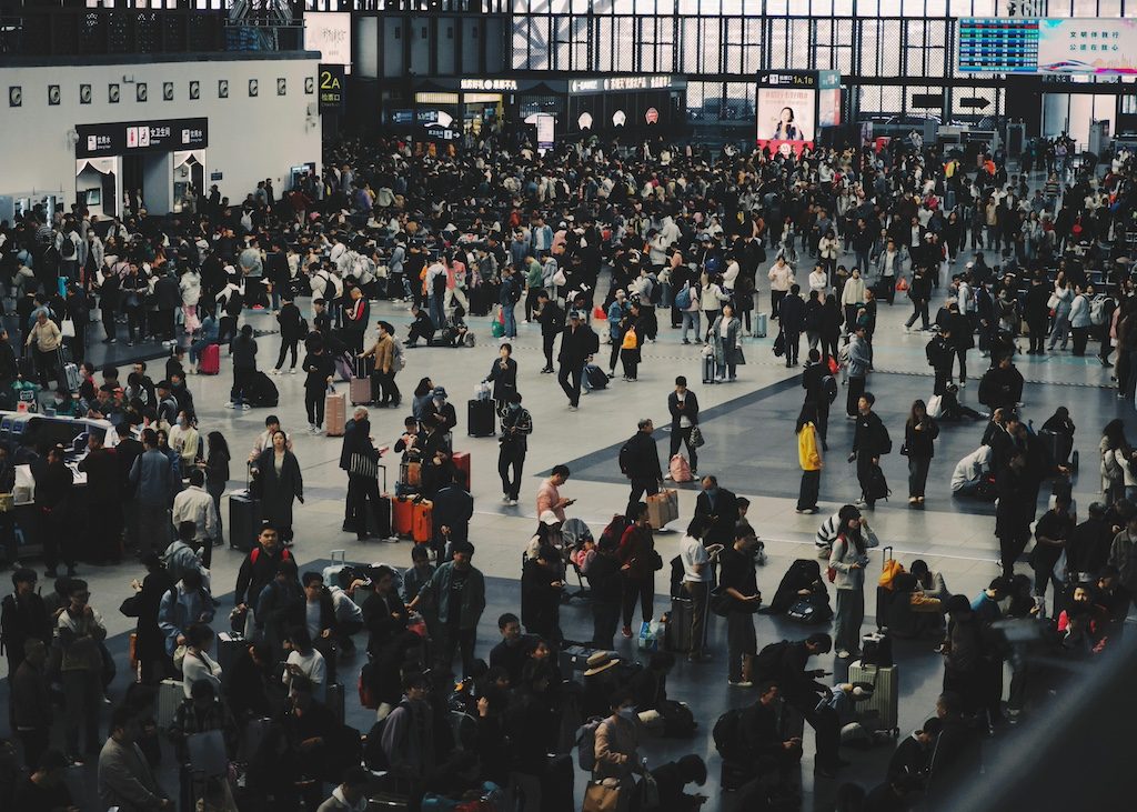 Large crowd of travelers in a busy airport terminal during peak hours