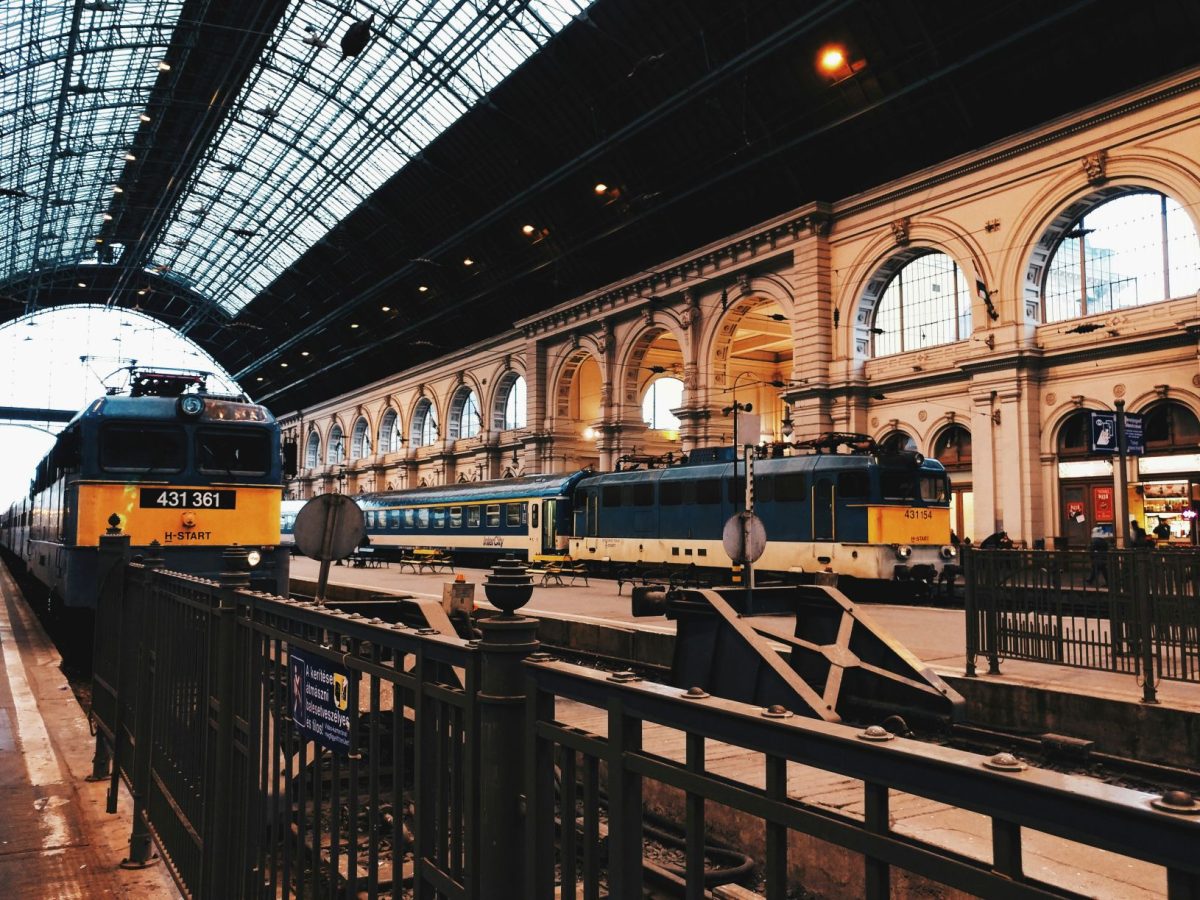 Yellow and black train at a European railway station with ornate architecture and glass roof