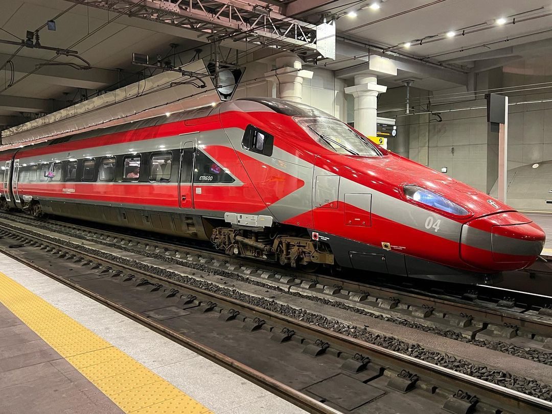 Red and black high-speed train at platform in modern station