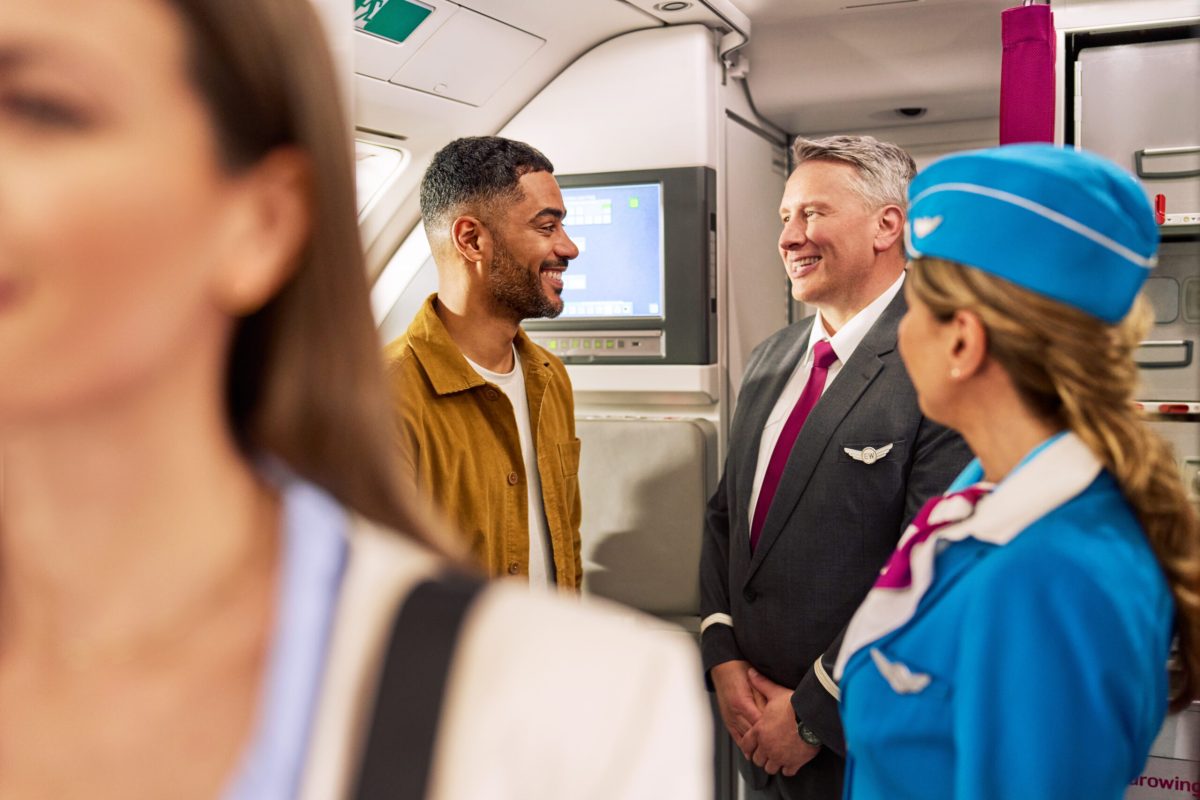 Eurowings crew members smiling with passengers on an aircraft.