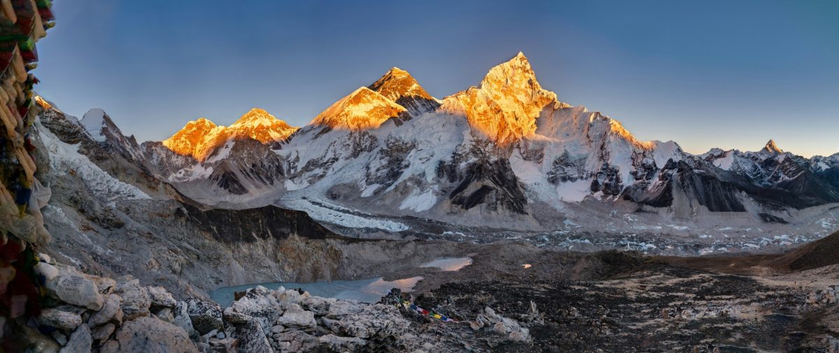 Mount Everest glows at sunrise, with base camp visible in the valley below.