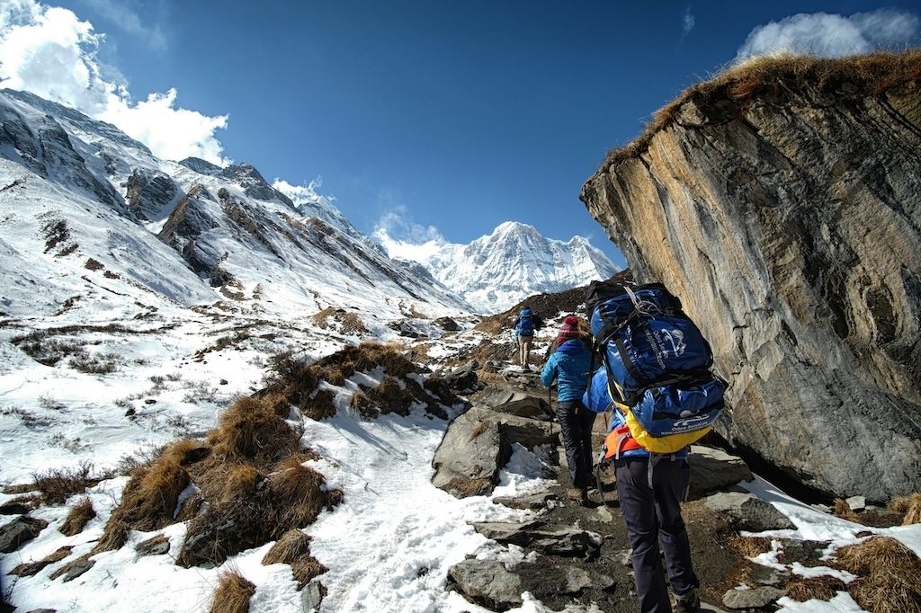 Trekkers hiking on snowy mountain terrain with snow-capped peaks in background
