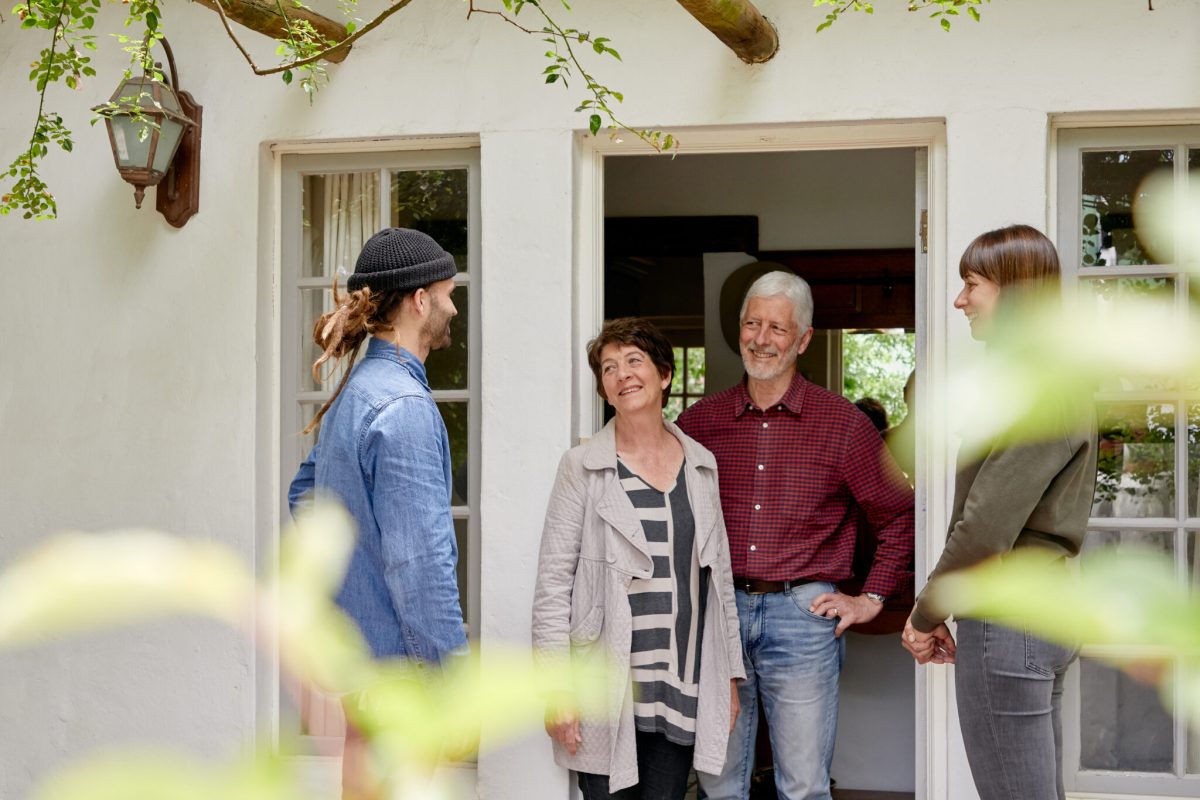 Family greeting guests at doorway of vacation home