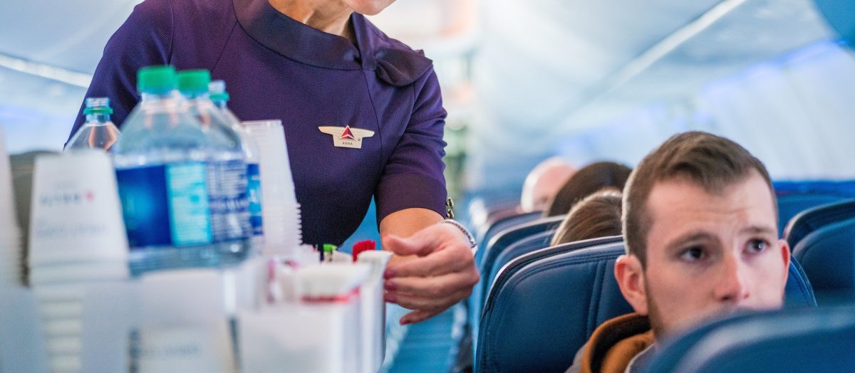Flight attendant serving beverages to passengers on an airplane