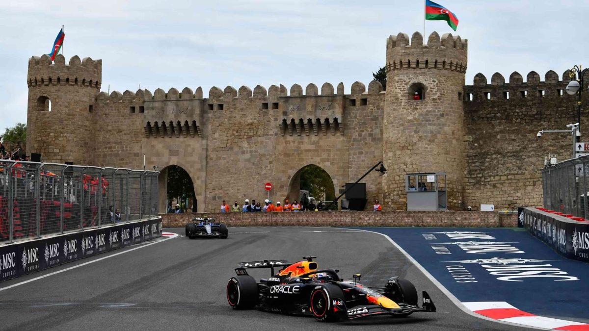 Formula 1 car speeds past Baku's Old City walls, with the Azerbaijani flag waving.