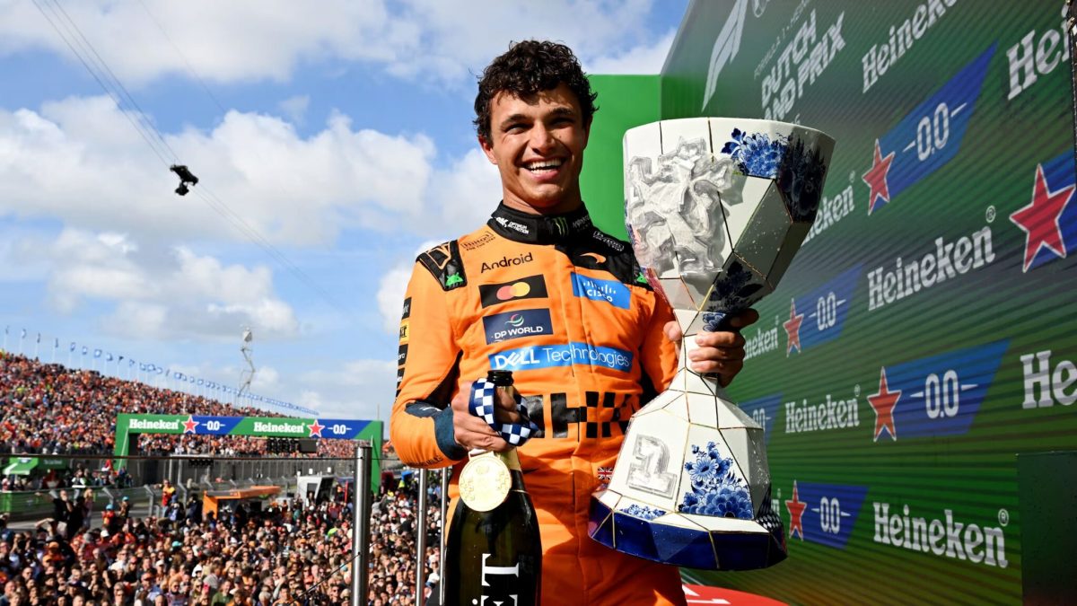Formula 1 driver on podium holding trophy at Zandvoort circuit with crowd