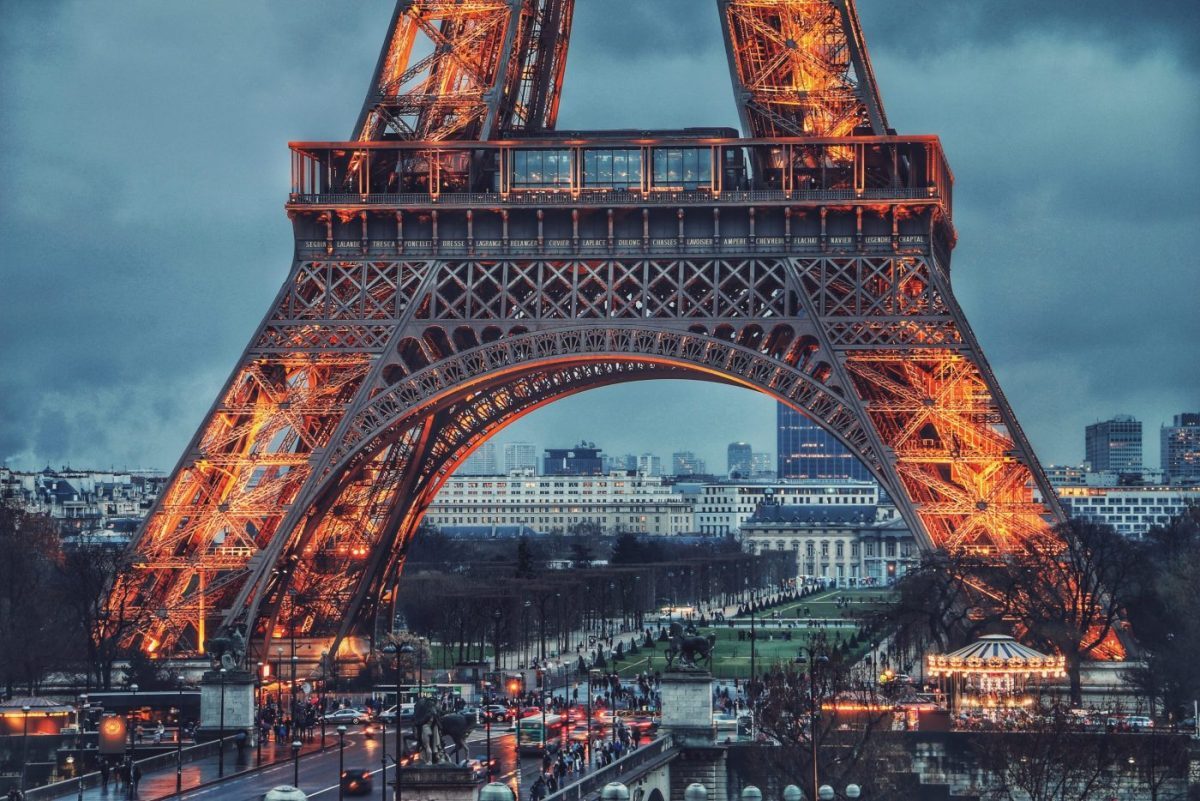 Illuminated Eiffel Tower at dusk with Paris cityscape and busy plaza below