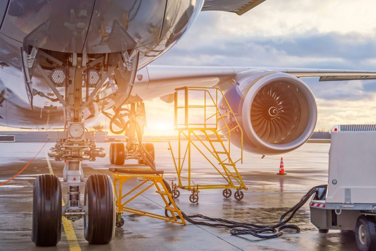 Commercial aircraft being refueled at airport gate during golden hour