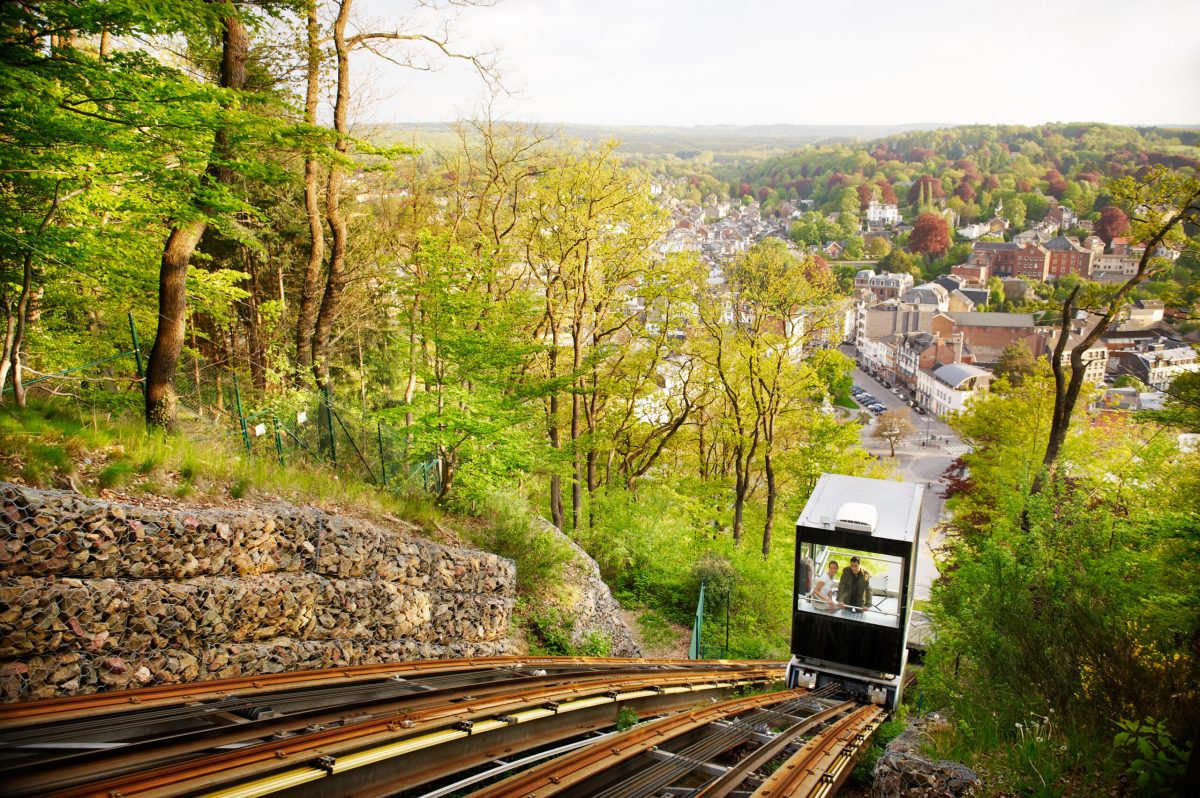 Funicular railway descending steep hillside toward town nestled in forested valley