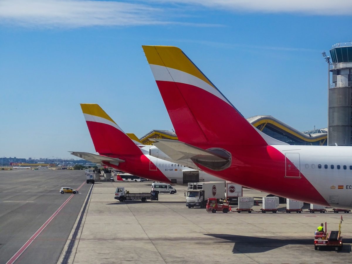 Iberia aircraft parked at airport terminal with distinctive red and gold tail fins