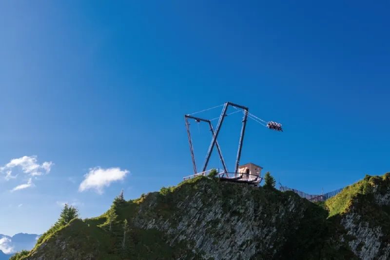 Giant swing suspended high above Alpine peaks against blue sky