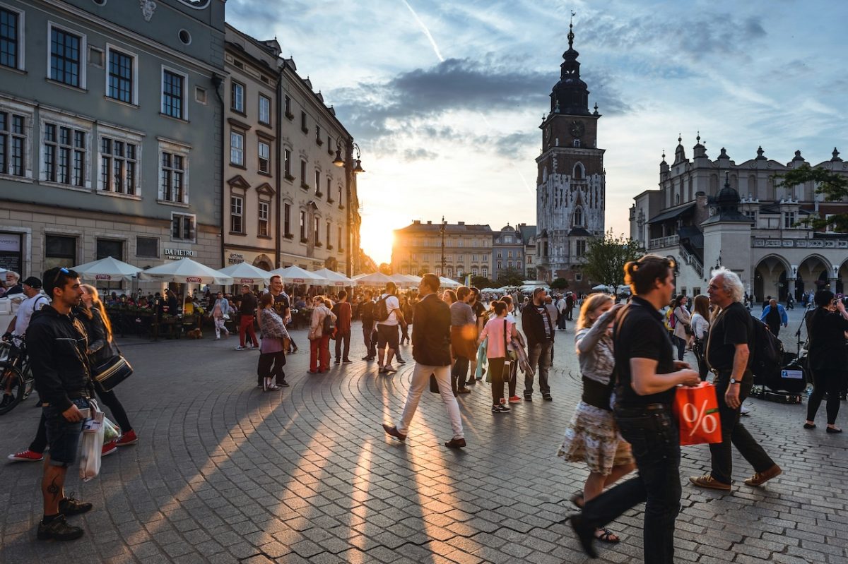 Crowded town square at golden hour with historic architecture and church tower