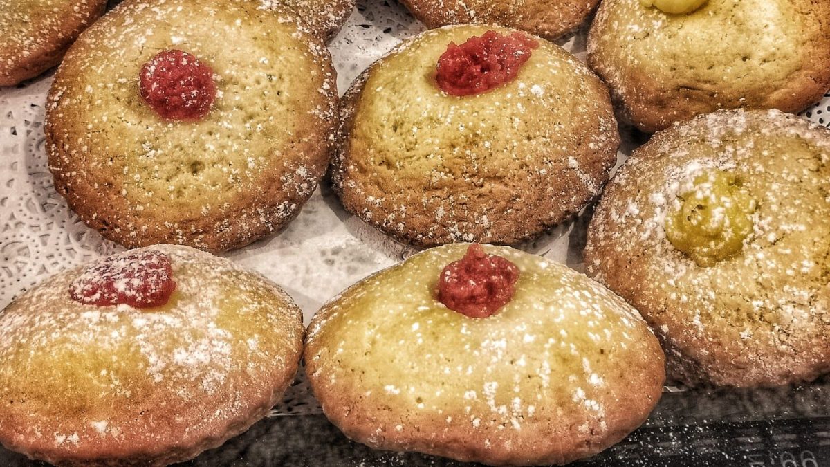Golden pastries dusted with powdered sugar and topped with red jam