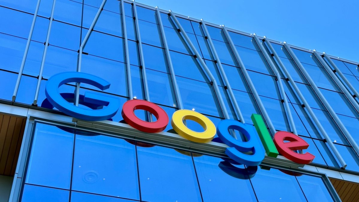 Google logo sign on modern glass building facade against blue sky