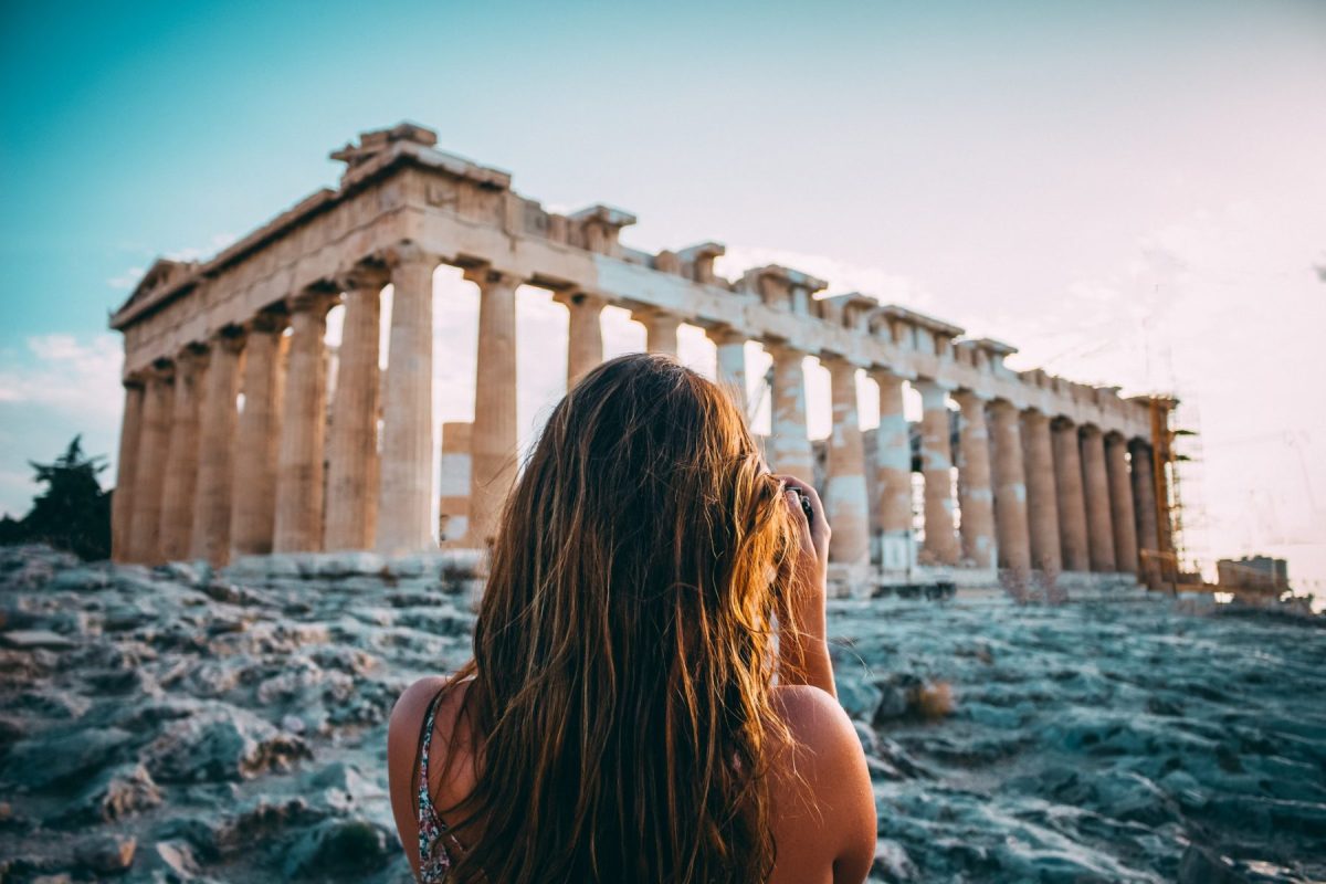 Woman with long dark hair viewing the Parthenon ruins in Athens at sunset