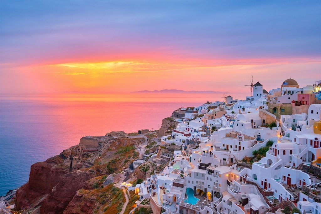 White-washed buildings of Santorini clinging to cliffs at golden sunset over the Aegean Sea