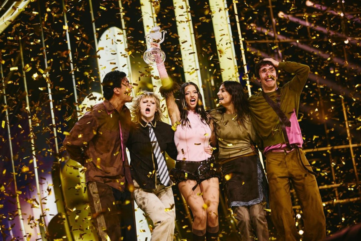 Group of people celebrating on stage with gold confetti falling around them