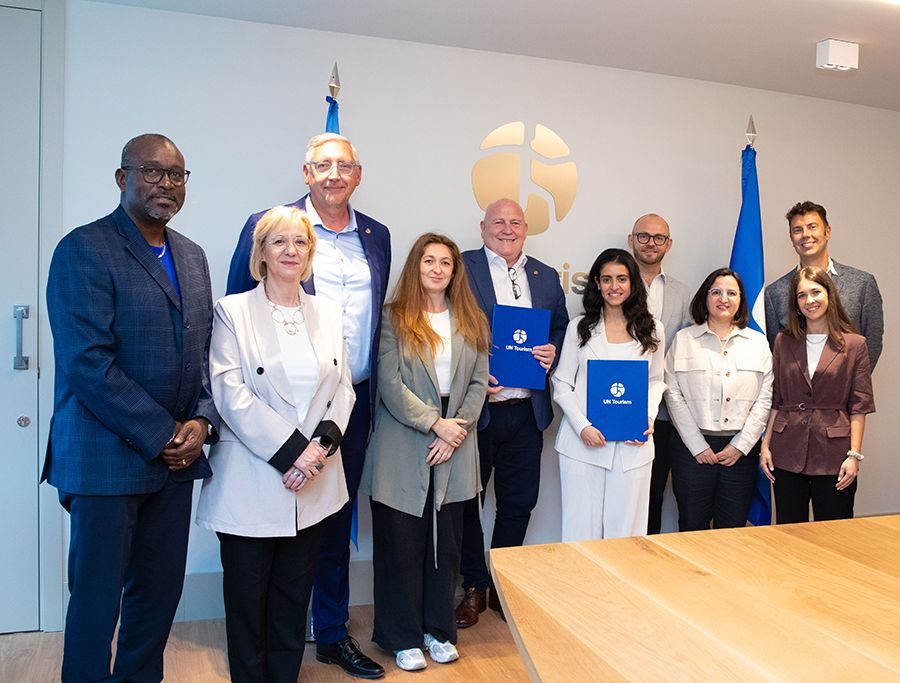 Group of professionals posing together at UN Tourism event with organizational flags in background