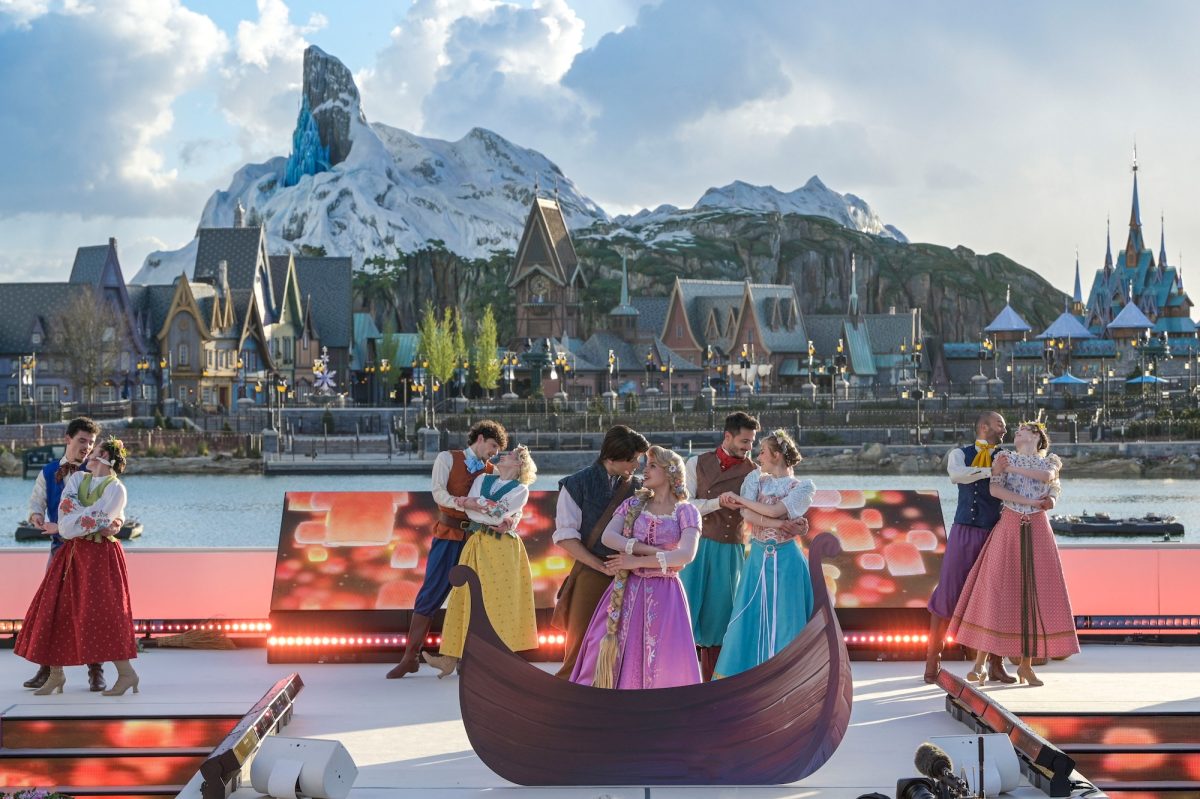 Guests in Disney princess dresses aboard a gondola at Disneyland Paris with snowy mountain backdrop