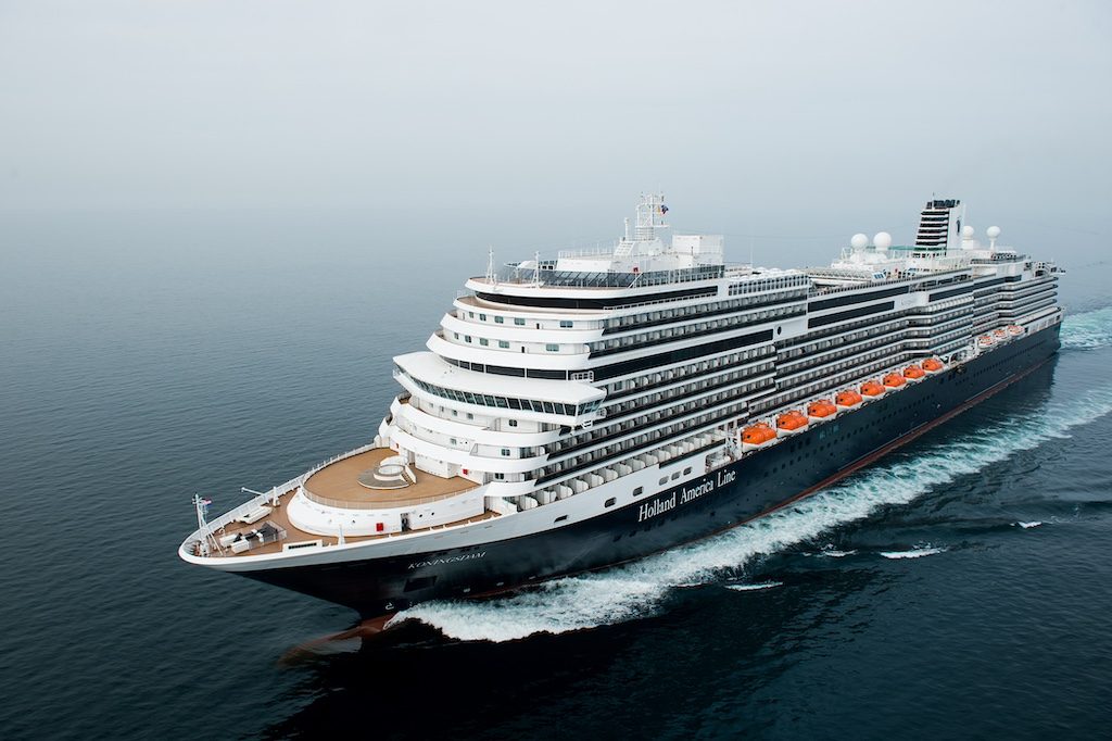 Large cruise ship with orange accent stripe sailing on open ocean