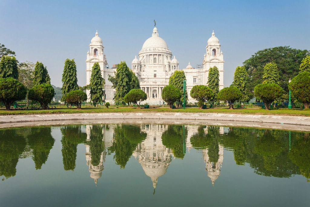 Victoria Memorial in Kolkata reflected in still water with manicured gardens