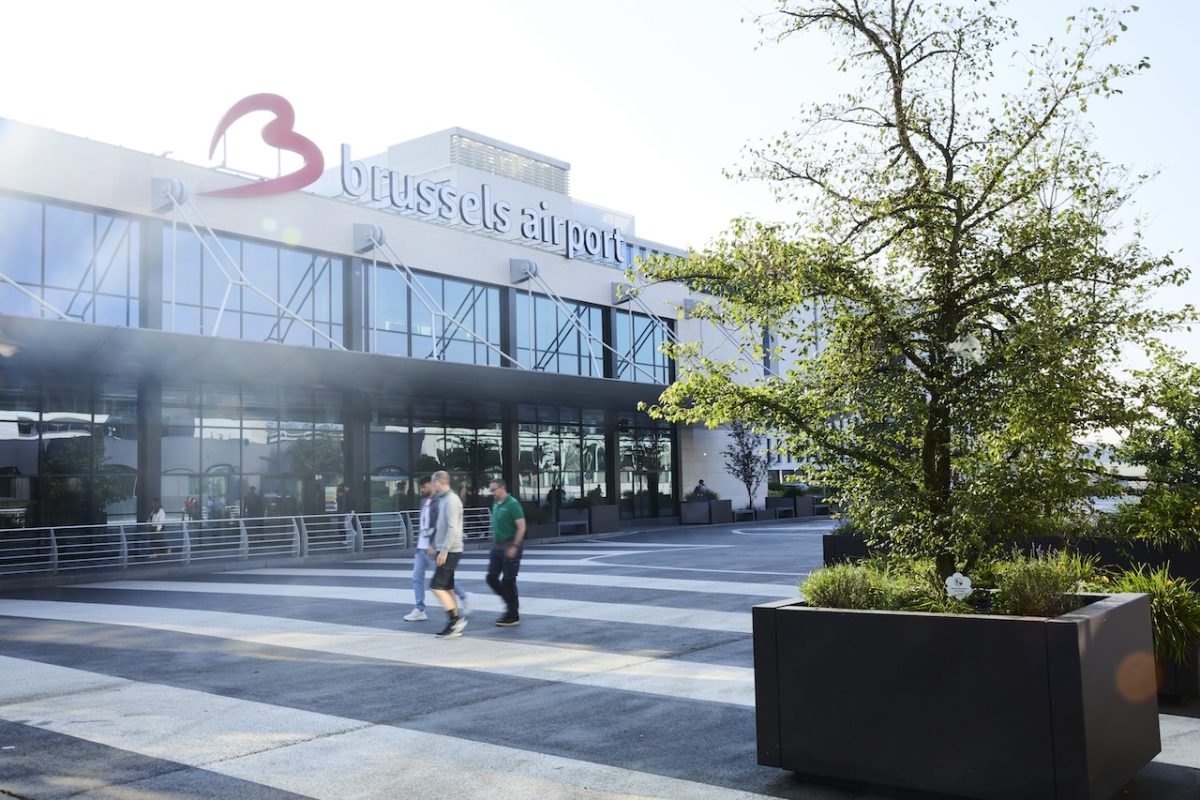 Brussels Airport terminal entrance with modern glass facade and pink logo signage