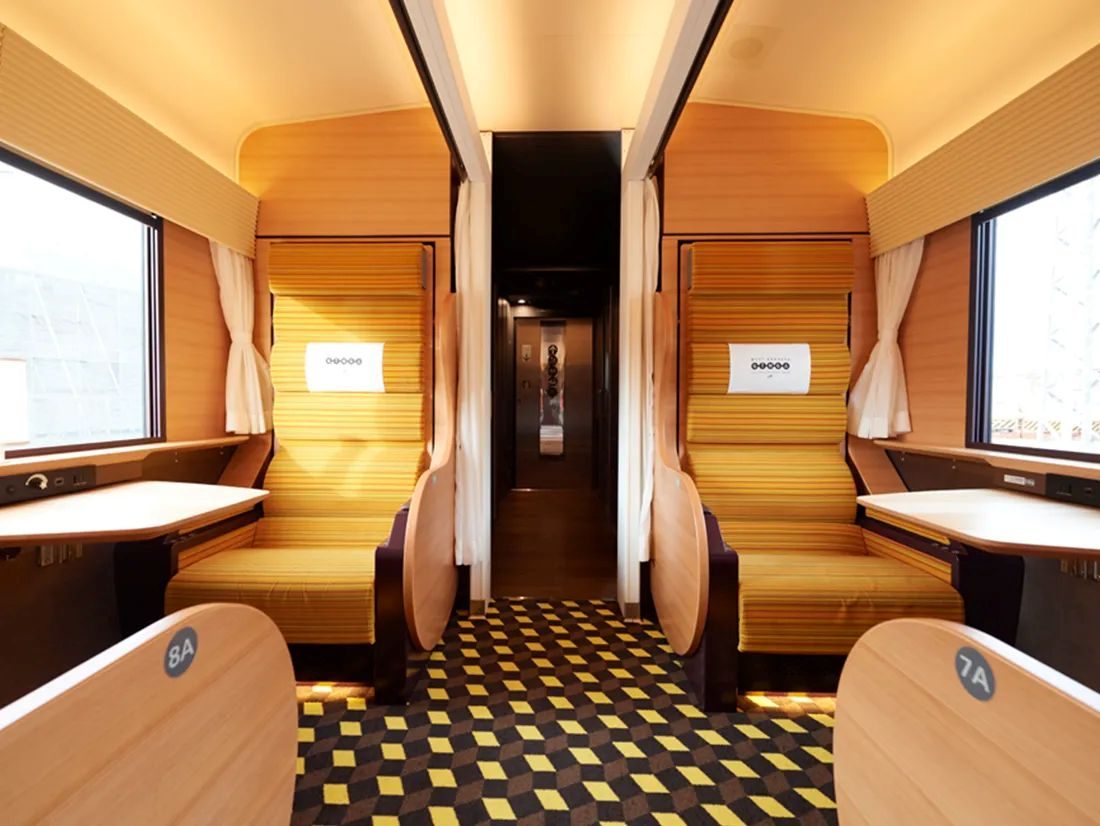 Interior of West Express Ginga sleeper train with wooden paneling and comfortable seating