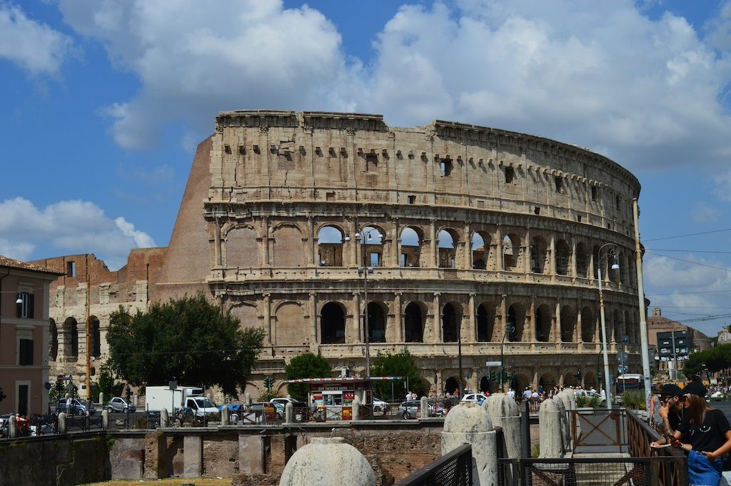 The Colosseum in Rome stands majestically under a blue sky with white clouds