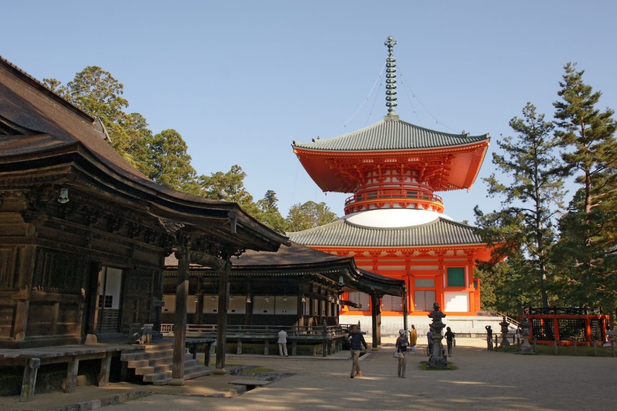 Traditional Japanese temple with red pagoda and wooden structures in serene courtyard