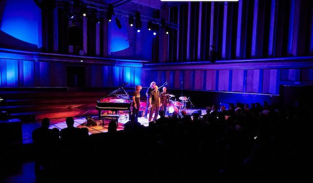 Jazz musicians performing on stage in Brussels venue with blue and red lighting