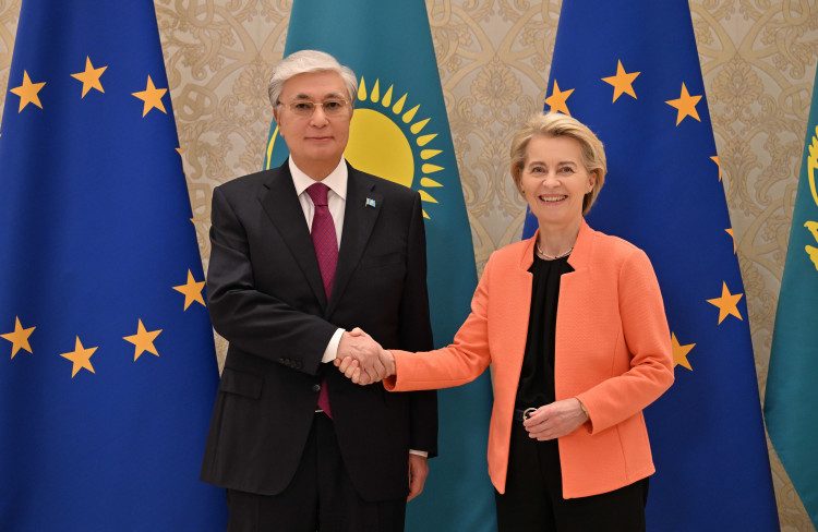 Kazakhstan and EU officials shake hands in front of EU and Kazakhstan flags