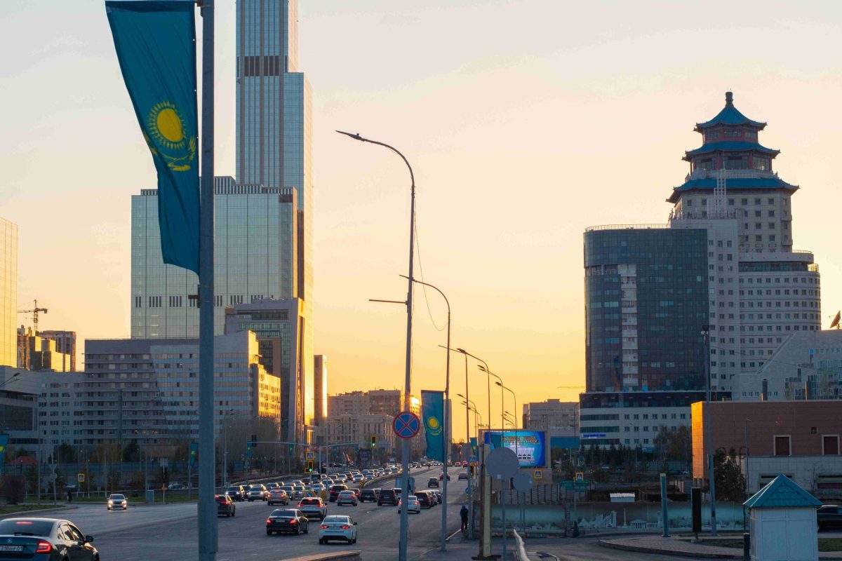 Astana skyline at sunrise with Kazakh flag, symbolizing growth and modern infrastructure.