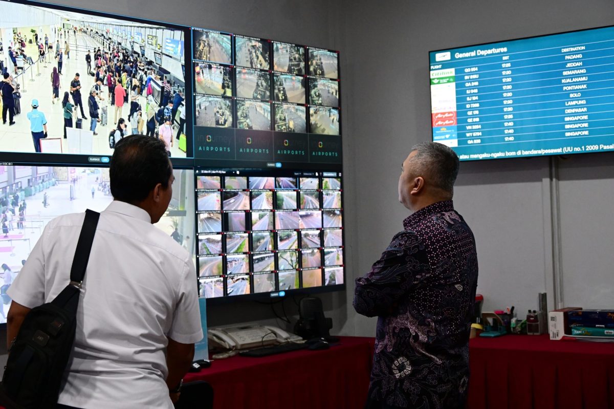 Travelers check flight information displays at an airport during travel disruptions