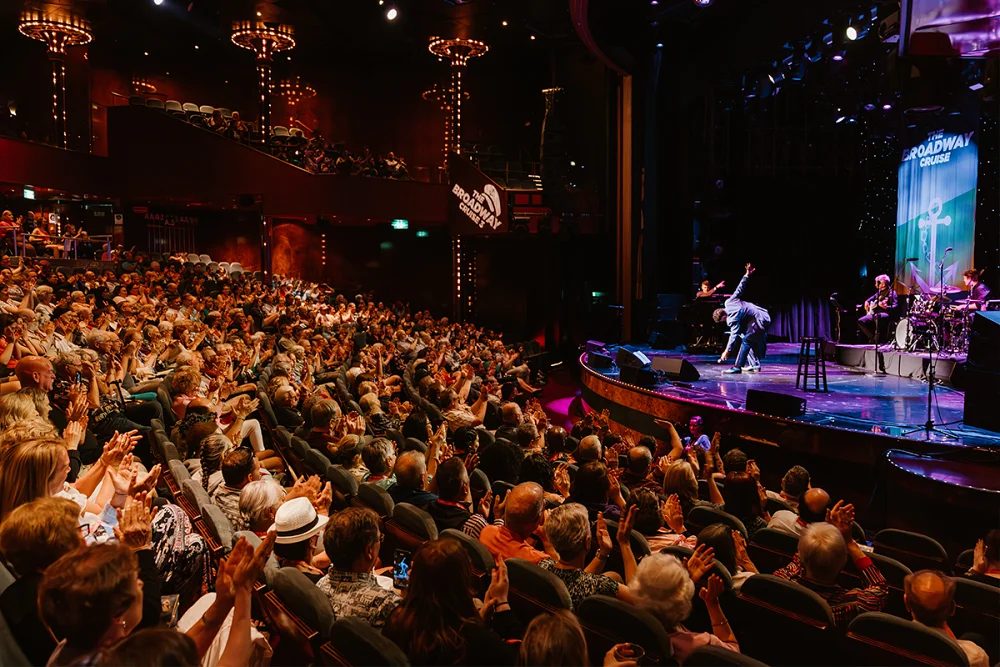 Large crowd of theater fans enjoying a Broadway-style performance on a cruise ship stage
