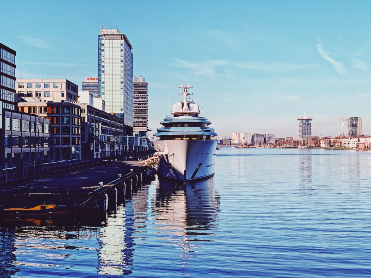 Large cruise ship docked at Amsterdam waterfront with city skyline in background
