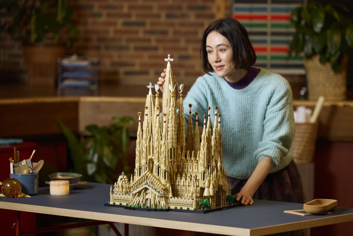 Woman admiring a large golden LEGO Sagrada Família model on a table