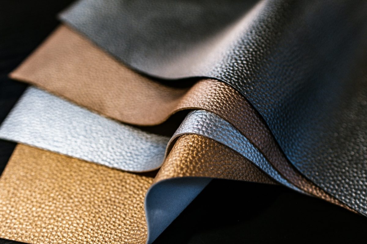 Layered samples of textured leather-like materials in tan, gray, and blue tones