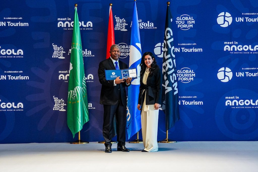 Officials at podium with flags during Angola tourism conference in Luanda