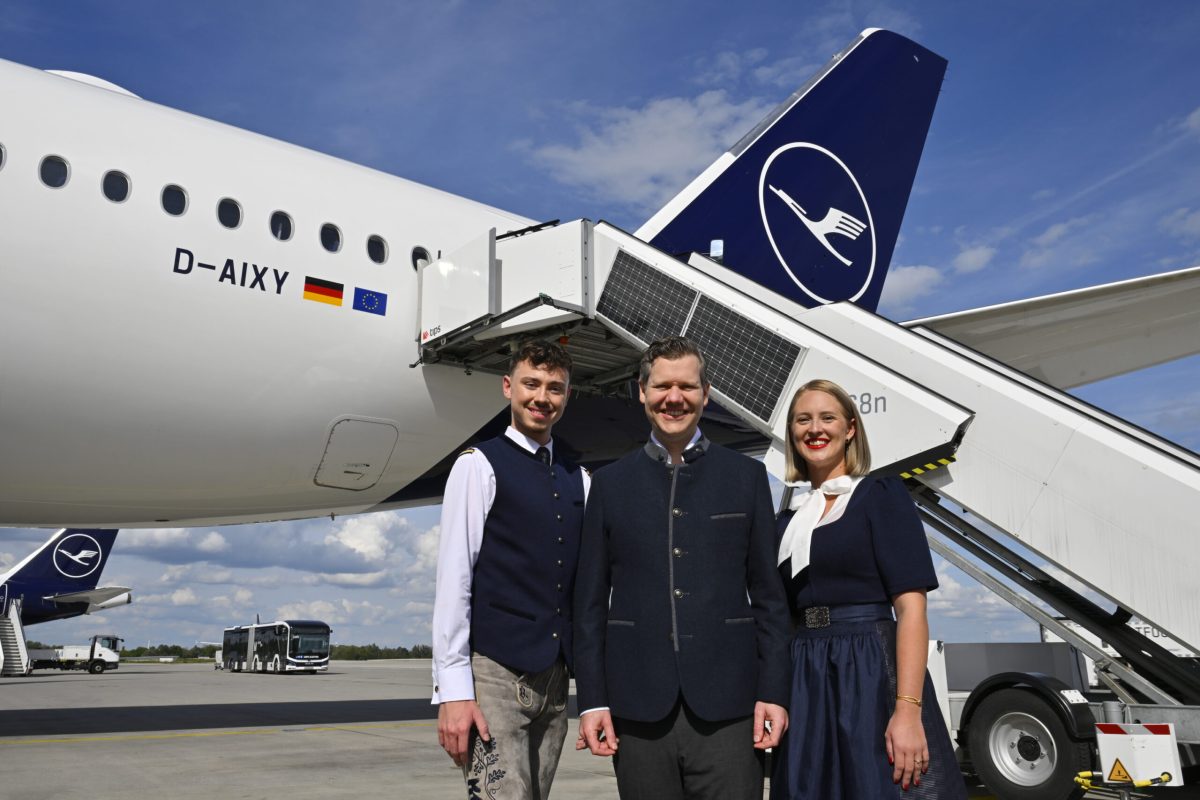 Lufthansa crew members in prototype Bavarian uniforms stand beside an aircraft.