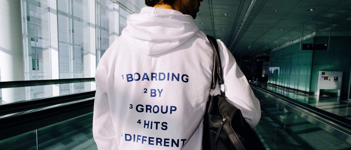 Person wearing white Lufthansa jacket with humorous flying etiquette text in airport terminal