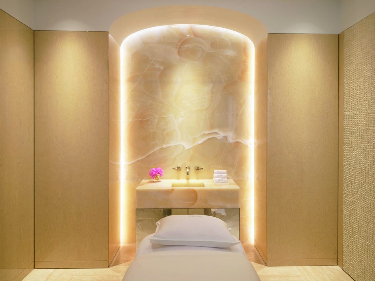 Luxurious spa treatment room with illuminated niche and massage bed at Dior spa