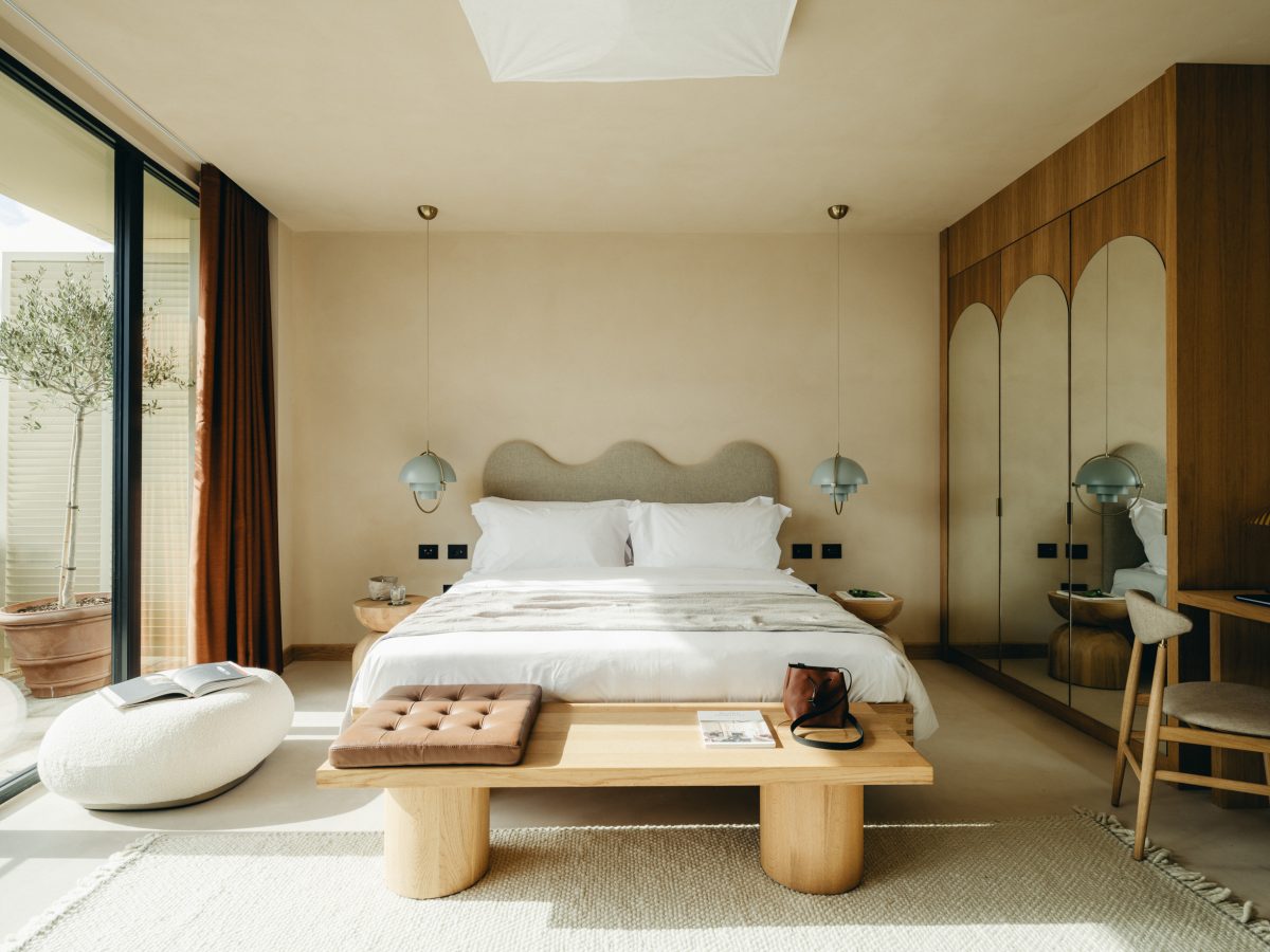 Luxury bedroom with wooden bed frame, cream bedding, and arched wooden wardrobe at Mamula Island resort