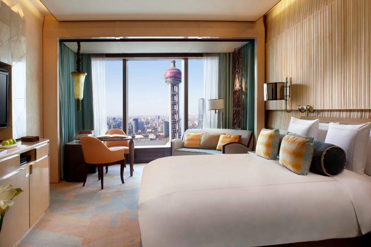 Luxury hotel bedroom with panoramic city skyline view through floor-to-ceiling windows
