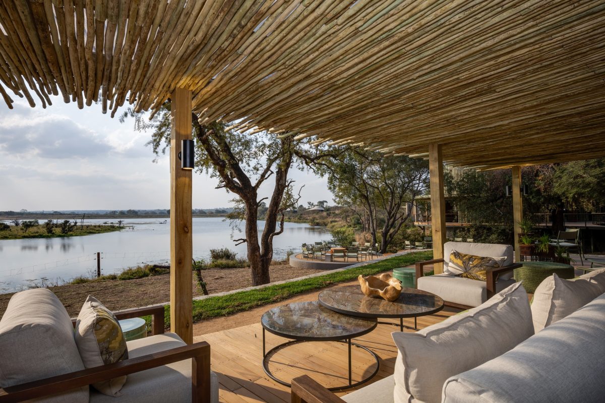 Luxury safari lodge overlooking a waterhole with comfortable seating and natural thatch roof
