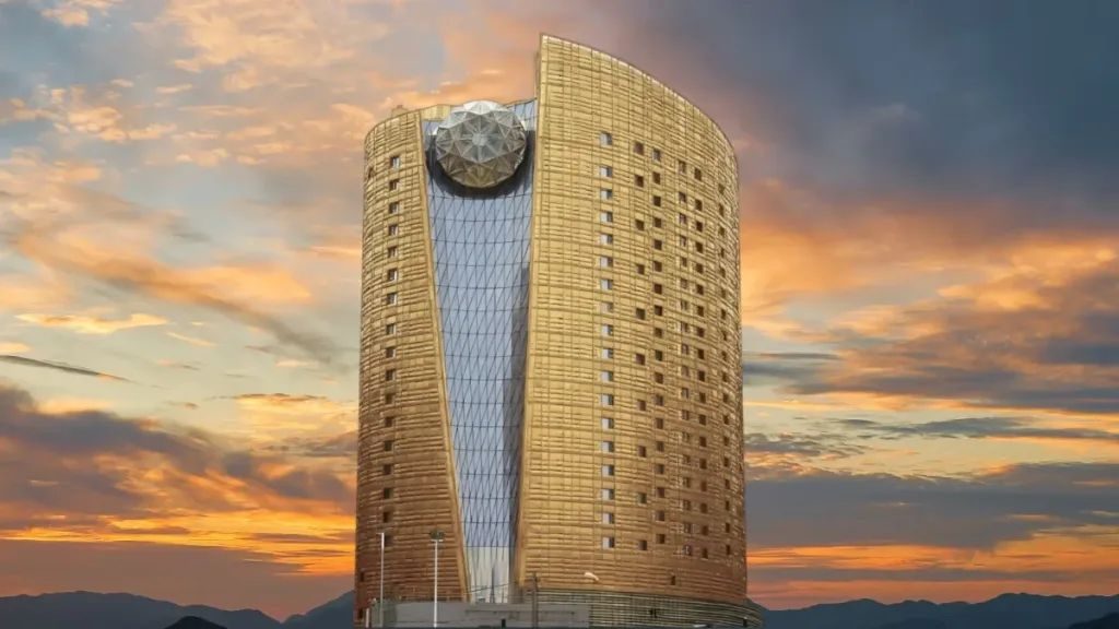 Golden luxury hotel tower with spherical crown structure against dramatic sunset sky