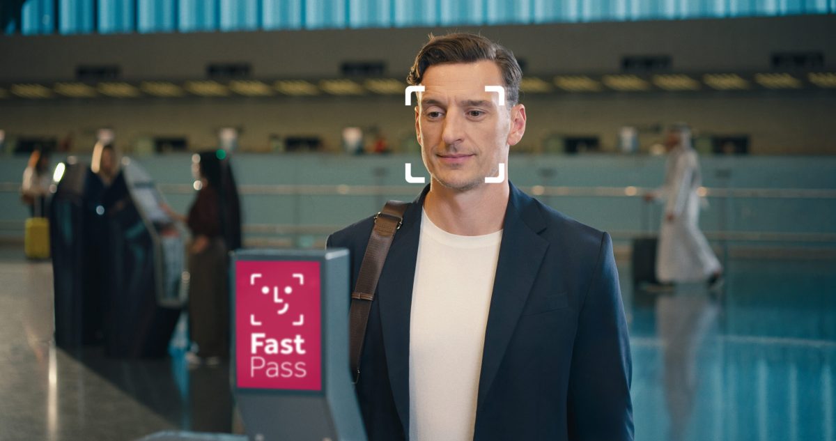 Man holding Qatar Airways Fast Pass card at modern airport terminal