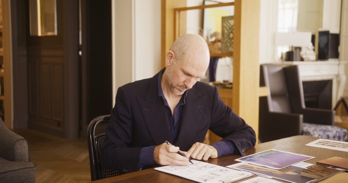 Man in business attire reviewing architectural plans and documents at desk
