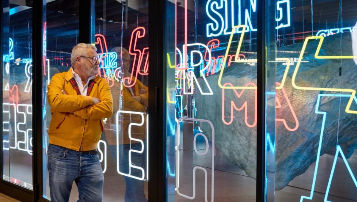 Man in yellow jacket viewing illuminated neon signage at Frankfurt Airport Terminal 3