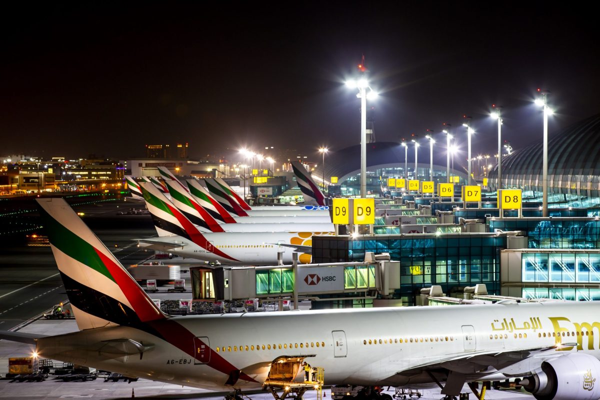 Aircraft parked at airport terminal at night with ground support vehicles